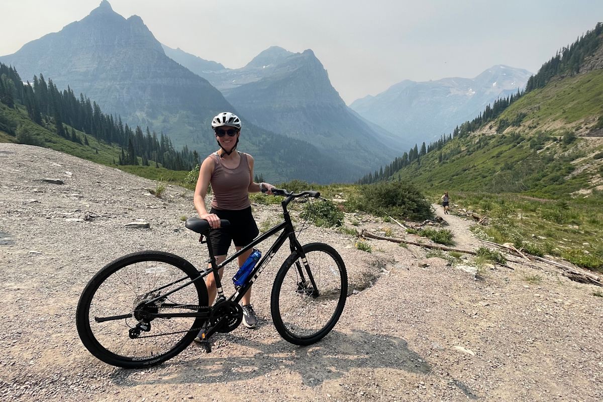 Guest posing with their bike in the Glacier National Park while on tour