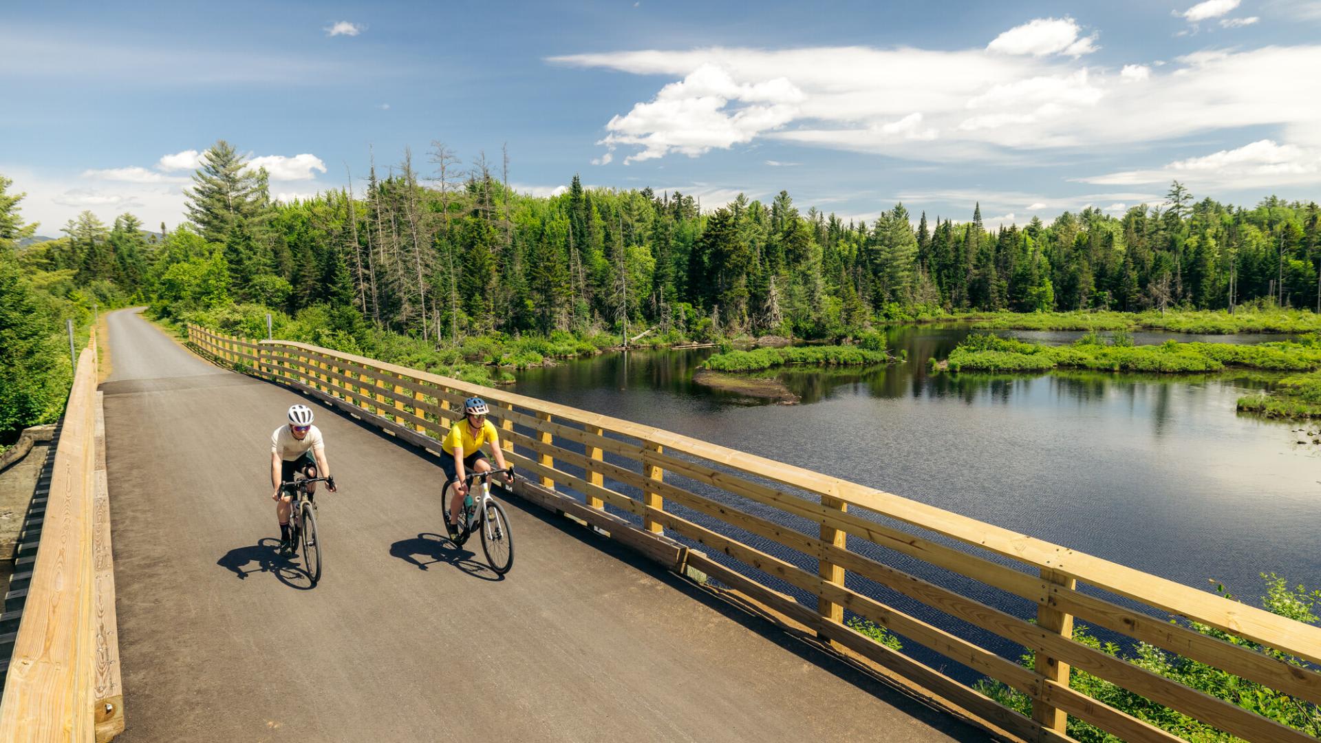 Guests biking over a bridge on the Adirondack Rail Trail Bike Tour